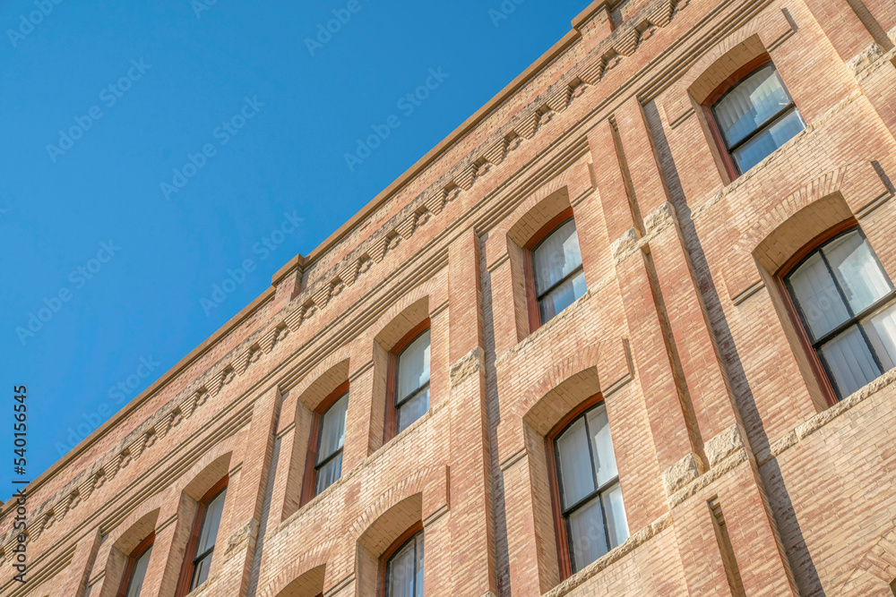 Building exterior with rectangular windows and brick wall against blue sky