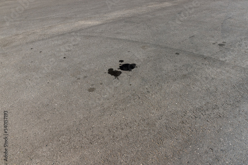 A road for vehicles covered with stains and pollution from oil and fuel of cars