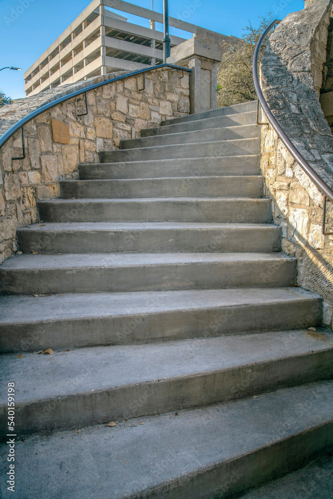 Outdoor stairway with stone half wall and railings in San Antonio River ...