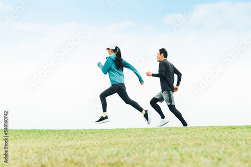 Fototapeta Naklejka Na Ścianę i Meble -  公園をスピードを出してダッシュでランニングするスポーツウェアを着たアジア人男女の後ろ姿
