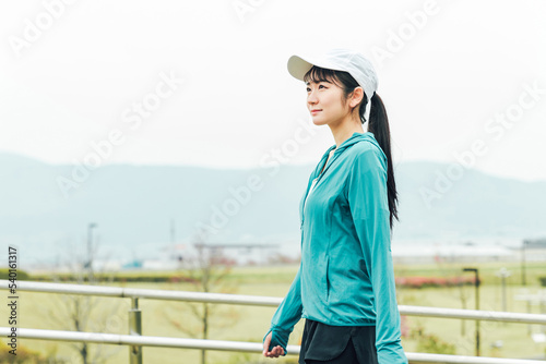 ダイエットのため公園でウォーキングするスポーツウェアのアジア人女性  © buritora