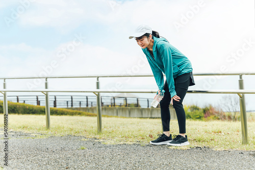 Obraz na płótnie ランニング・ウォーキング中に息切れ・疲労・めまいで困るスポーツウェアのアジア人女性 