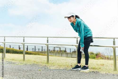 Photos 運動中に呼吸困難・喘息・息切れで苦しくて困るスポーツウェアのアジア人女性