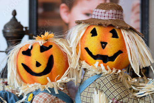 two pumpkin head scarecrow on display next to a babys portrait © Klarion