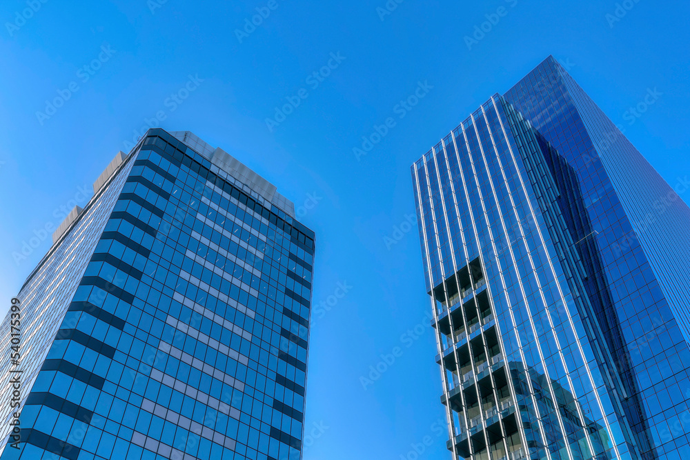 Facade of buildings with glass exterior towering against the clear blue sky