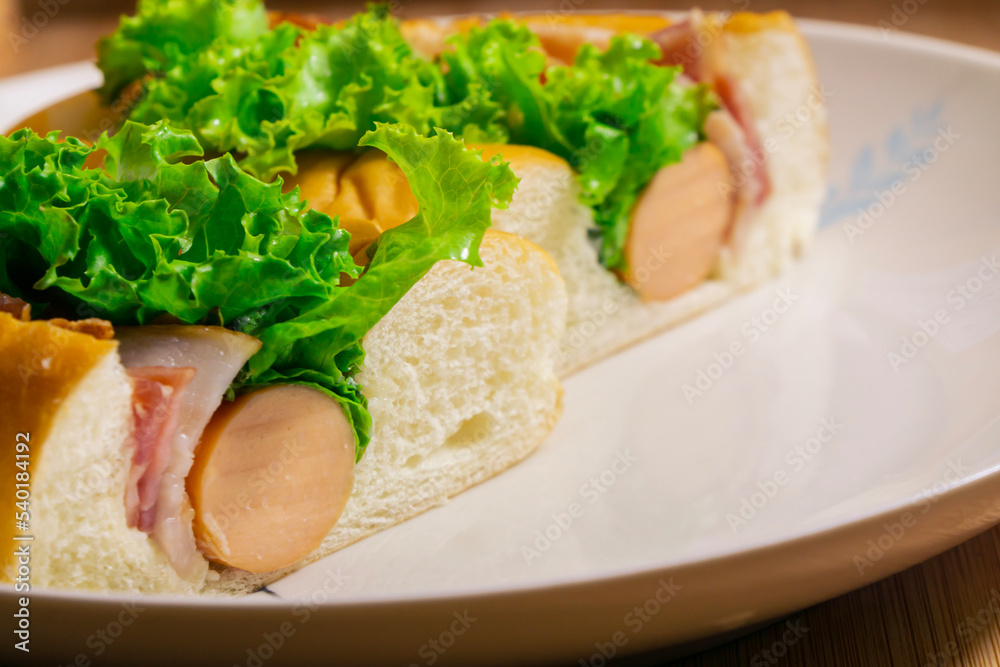 Hotdog with bacon and sausage on white plate
