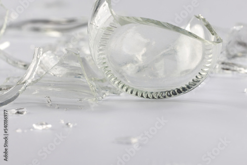 Photography A glass bottle broken into many fragments on a gray background.