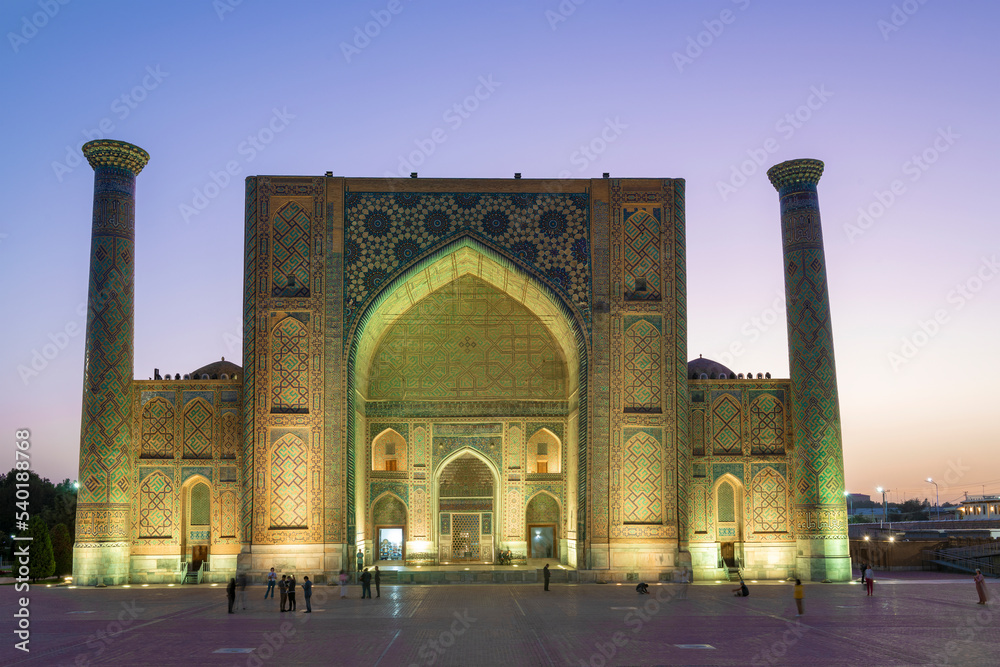 Facade of Ulugbek medieval madrasah at evening twilight. Samarkand, Uzbekistan