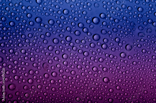 Water drops on glass as a background. Condensation on a cold drink. Multicolored background with drops texture.