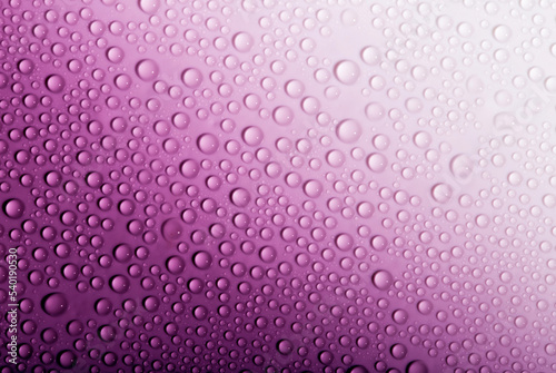 Water drops on glass as a background. Condensation on a cold drink. Purple background with drops texture.
