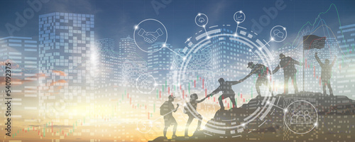 Silhouette of a group of people helping each other to the top of the mountain. Digital building background and sunset sky. Financial business graphs and icons. Cooperation for the success.