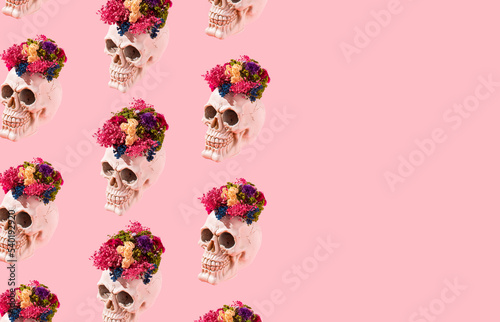 Modern idea made of skull with colorful dried flowers on pastel pink background. Minimal pink Halloween or day of the dead concept. Skull pattern with copy space.