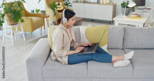 Woman student, study online with laptop and typing essay research report for university education. Elearning course, college assignment and listening to lecture on headphones on living room sofa home photo