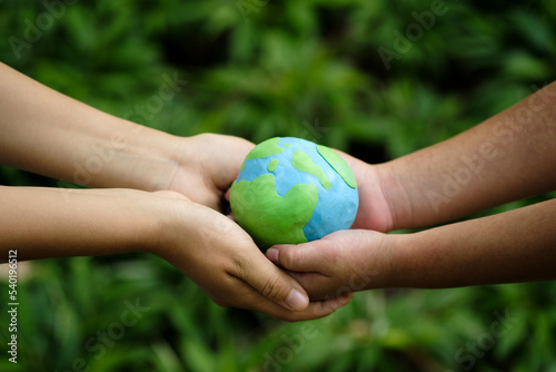 Fototapeta Naklejka Na Ścianę i Meble -  Green Energy, ESG, Renewable and Sustainable Resources. Environmental Care. Hands of People Embracing a Handmade Globe. Protecting Planet Together. World Earth Day Concept.