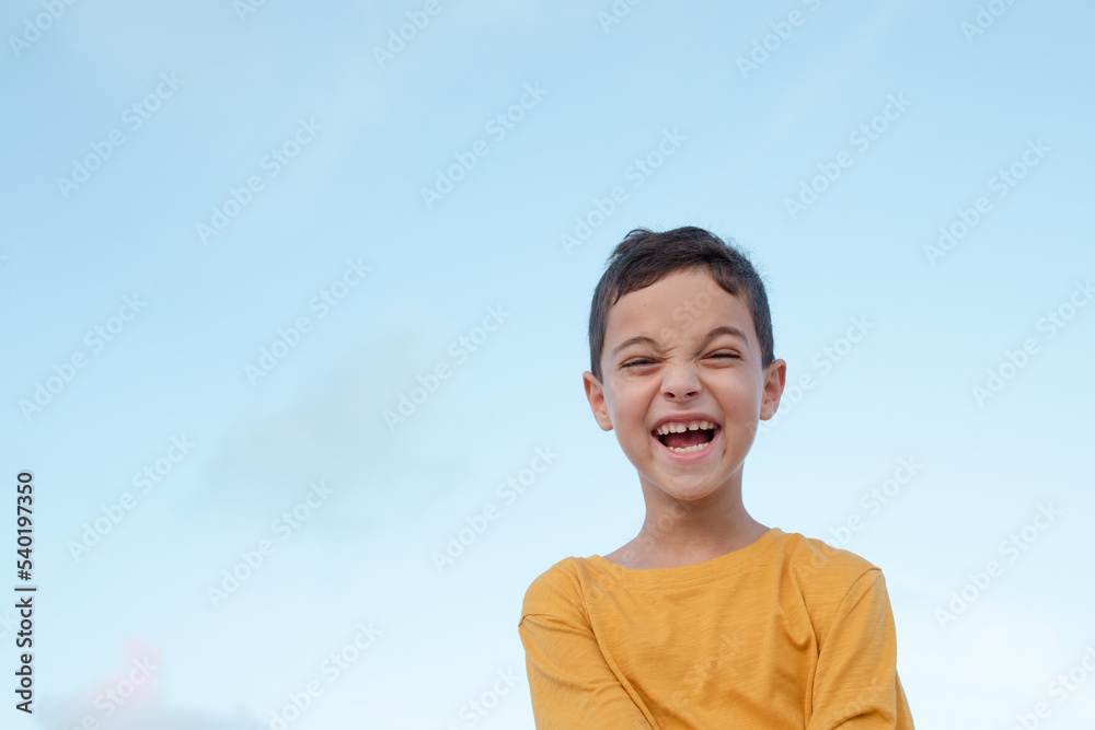 Cheerful positive child, blue sky on the background. Funny face of a boy 8 years old. Emotion concept, facial expression, holidays, funny baby face. Isolated. Brunette person, caucasian. Cheerful positive child, blue sky on the background. Funny face of a boy 8 years old. Emotion concept, facial expression, holidays, funny baby face. Isolated. Brunette person, caucasian.