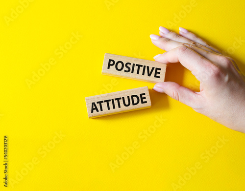 Positive attitude symbol. Concept words Positive attitude on wooden blocks. Beautiful yellow background. Businessman hand. Business and Positive attitude concept. Copy space.
