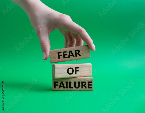 Fear of failure symbol. Concept words Fear of failure on wooden blocks. Beautiful green background. Businessman hand. Business and Fear of failure concept. Copy space.