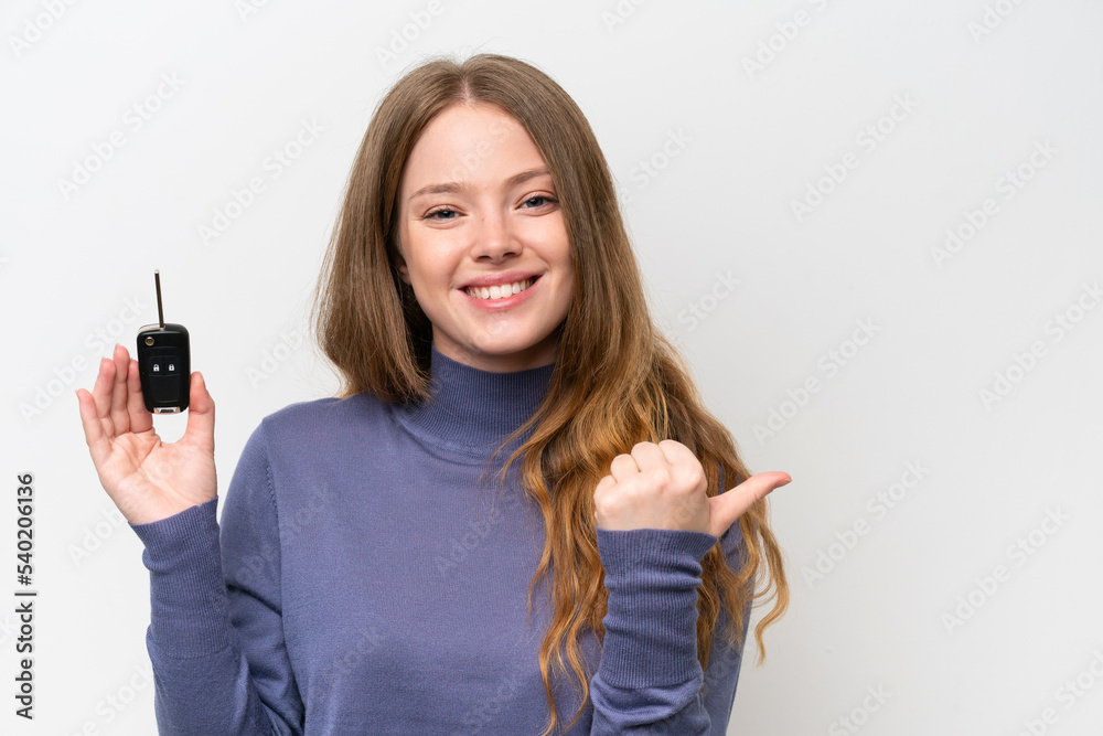Young caucasian woman holding car keys isolated on white background pointing to the side to present a product