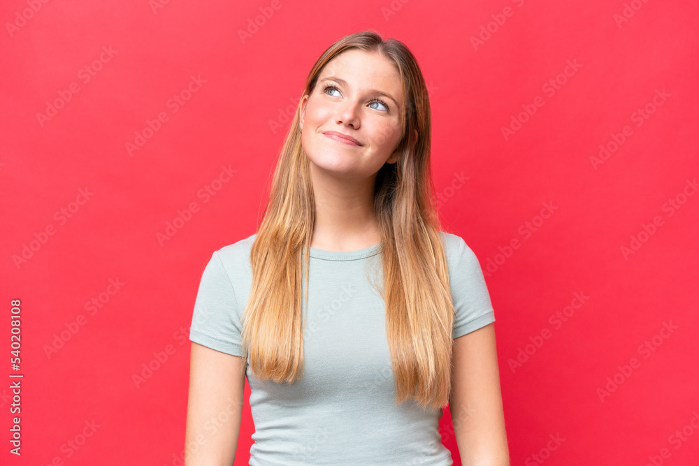 Young beautiful woman isolated on red background thinking an idea while looking up