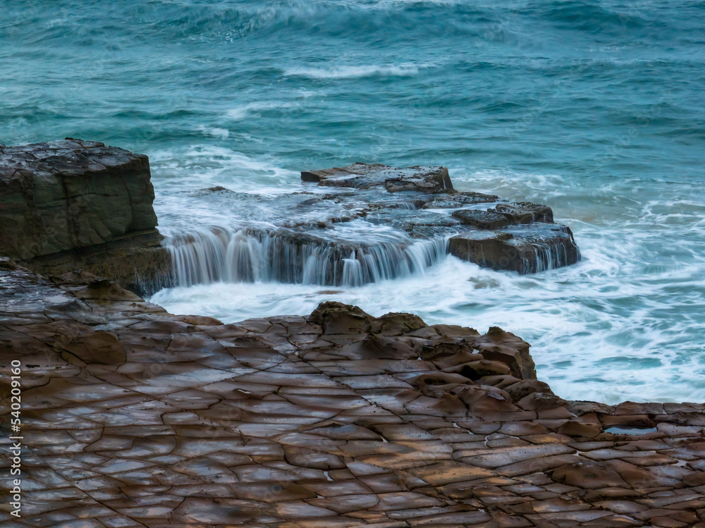 Top down seascape, water cascades and rock platform