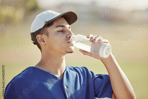 Fitness, water bottle and athlete drinking liquid for thirst, hydration and health while training. Sport, exercise and baseball player enjoying a refreshing drink while practicing on an outdoor field