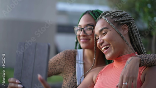 Two young black women taking selfie with tablet. African American girlfriends with braided hairstyle holding device outdoors 2
