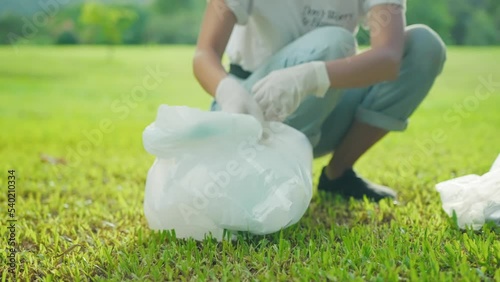 Low angle shot of female volunteer pickup recycle trashes from green grass, green eco concept, preventing global warming, utilizing reusable materials for sustainable nature, rubbish waste management.