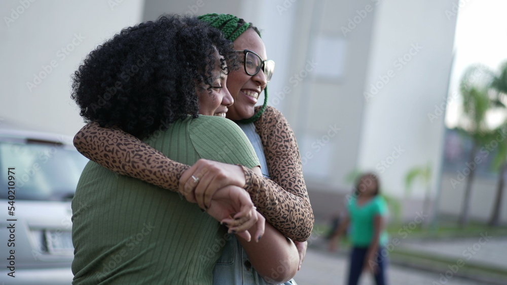 Two happy Brazilian black women laughing and smiling together. Fun adult girls embrace standing outdoors. Friendship concept Two happy Brazilian black women laughing and smiling together. Fun adult girls embrace standing outdoors. Friendship concept