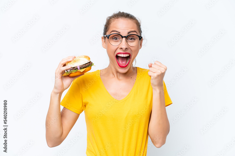 Young caucasian woman holding a burger isolated on white background celebrating a victory in winner position Young caucasian woman holding a burger isolated on white background celebrating a victory in winner position
