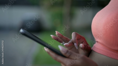 Closeup female hands holding tablet device touching screen with finger outdoors