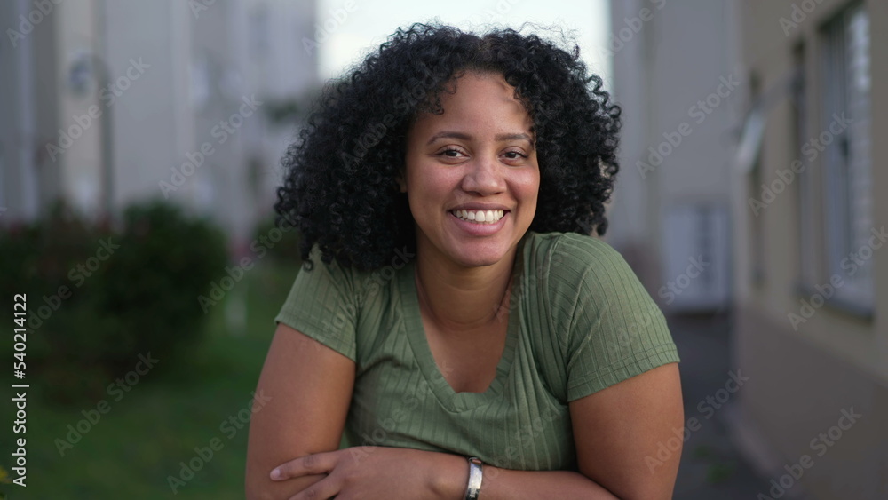 Fototapeta premium One happy young black latina woman smiling at camera. A Brazilian African American female person with curly hair closeup face