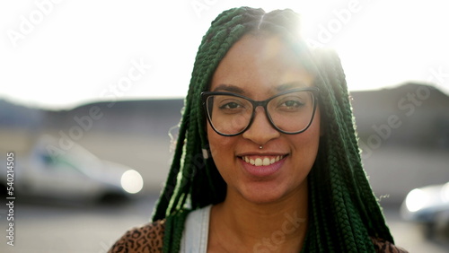 Millennial adult girl with box braided hairstyle portrait face closeup looking at camera outdoors in sunlight. young Brazilian woman photo