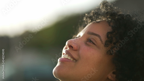 Meditative young woman opening eyes smiling to sky. One contemplative hispanic Brazilian female person in contemplation feeling free