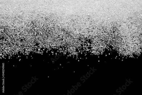 Białe kryształy cukru rozsypane na czarnym tle photo