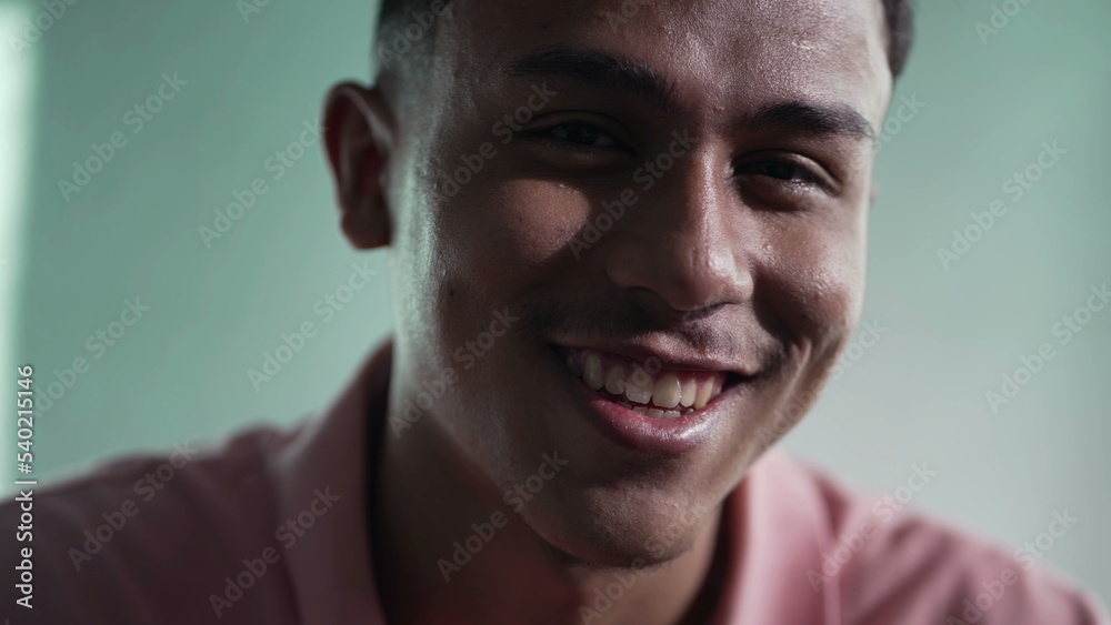 Fototapeta premium One happy hispanic young man closeup face. Portrait of a South American Brazilian male person looking at camera smiling indoors