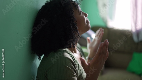 One Evangelical young black woman in praying to GOD raising hands in the air surrendering to a higher power