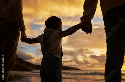 Parents, child and silhouette of holding hands on the beach during sunset for family bonding in the outdoors. Kid hand, mother and father enjoying the scenic view, care and freedom on the ocean coast