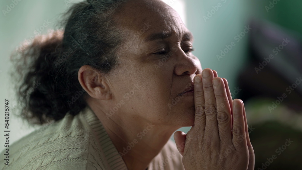 Older woman praying to God at home. One hispanic senior lady in prayer closeup face. Hispanic South American person Older woman praying to God at home. One hispanic senior lady in prayer closeup face. Hispanic South American person