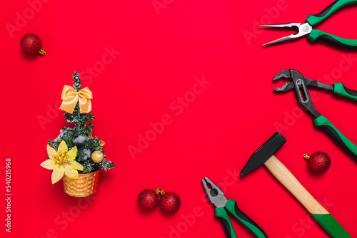 A set of quality green building tools to repair a car or house and Christmas tree on a red background. Do it yourself instruments. Banner for a New year advertise construction shop with copy space