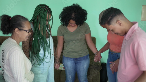 Group of hispanic family praying at home holding hands together. A latin South American friends in prayer