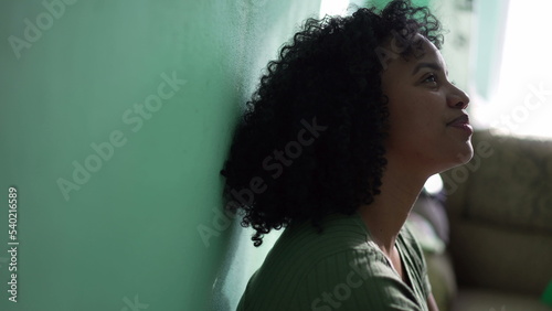 Fotografi A hopeful South American Brazilian latina black girl leaning on green wall having trust in prosperity