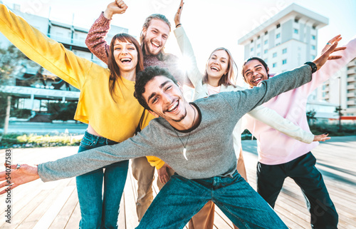 Multiracial young people group with hands up smiling at camera together - Happy friends hanging out on city street - Friendship concept with guys and girls having fun outside