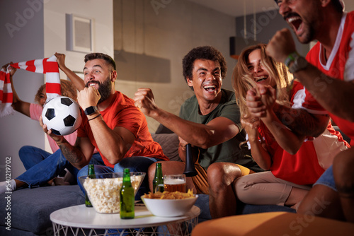 Fotografie Football fans watching game on TV celebrating their team victory