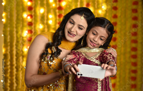 Happy young woman and daughter celebrating diwali and taking selfie
