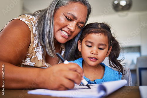 Girl homework, learning and grandmother helping child with school education in a notebook in their home. Kid and senior woman, creative drawing or homework writing for knowledge and learning alphabet photo