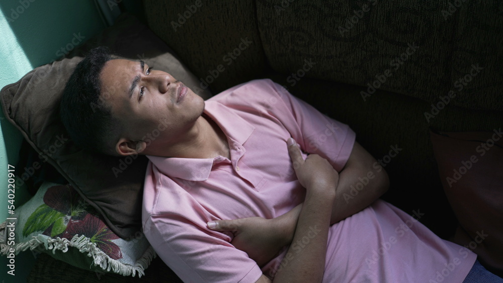 One pensive hispanic man lying on couch in contemplation. Thoughtful person thinking One pensive hispanic man lying on couch in contemplation. Thoughtful person thinking