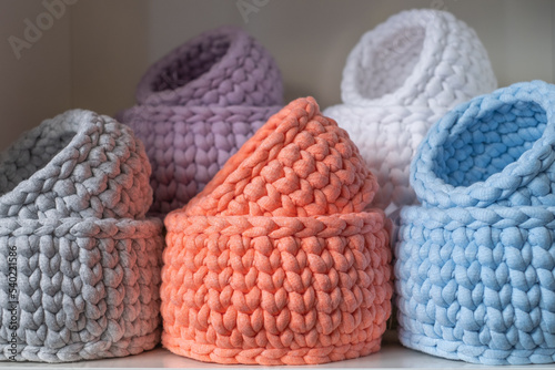 close-up of a beautiful colourful crochet baskets, cozy interior, jewellery storage. place for your text. Sustainable, organic lifestyle advertising. Poster for handicrafts.  © Silga