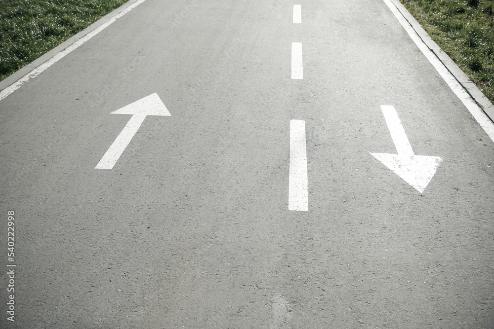 Two white arrow signs on opposite direction on asphalt road. Both sides sign. Up and Down arrows. Direction for traffic safety way. Pointer on gray asphalt floor. Two white arrow signs on opposite direction on asphalt road. Both sides sign. Up and Down arrows. Direction for traffic safety way. Pointer on gray asphalt floor.
