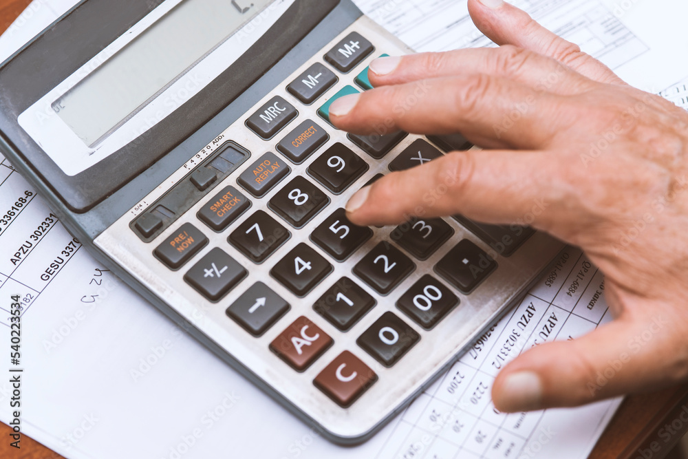 close up of a businessman's hand with a calculator and documents close up of a businessman's hand with a calculator and documents