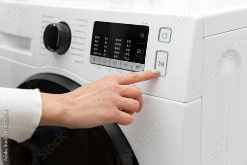 Cropped female hands choosing wash settings on a modern digital display.